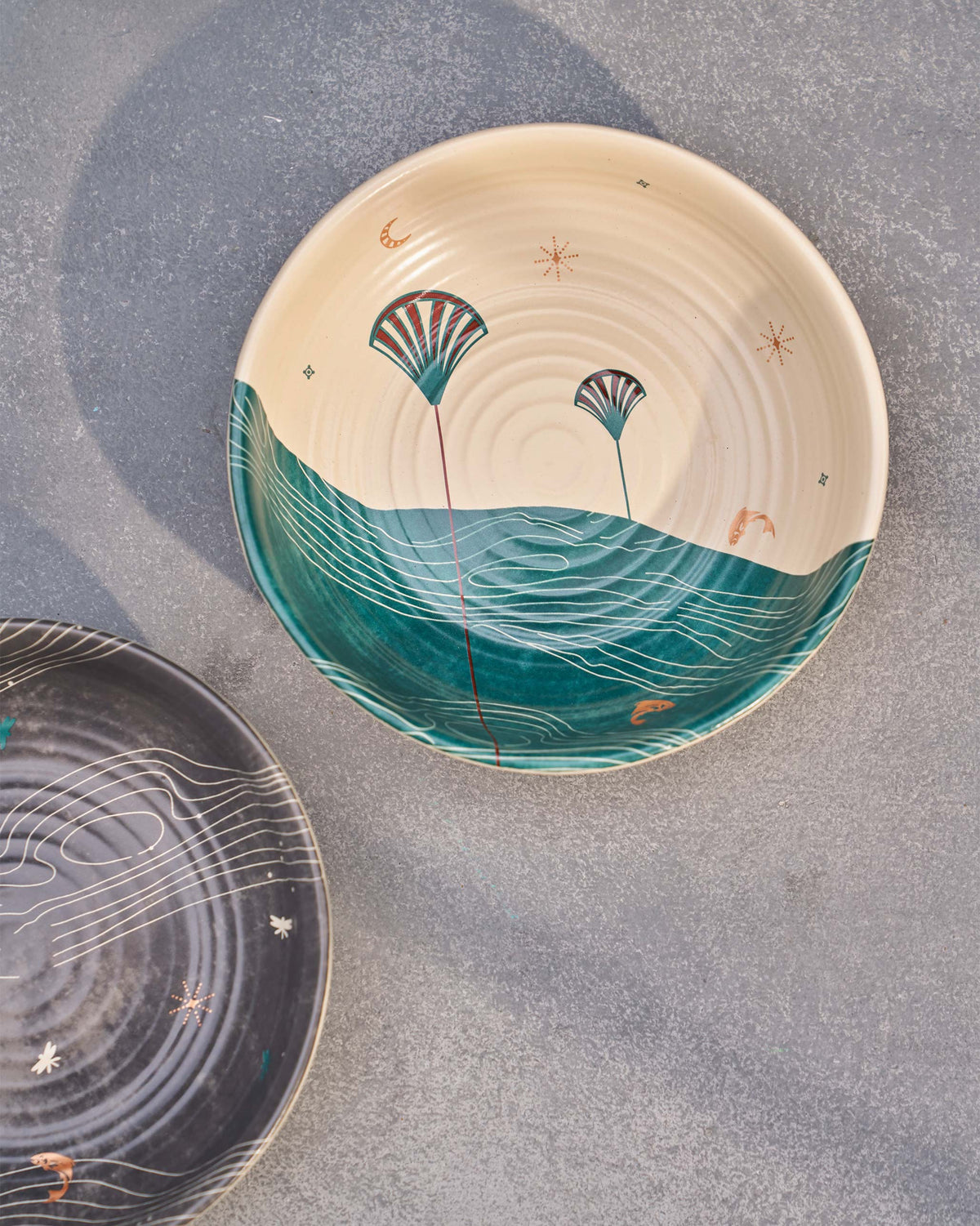 Overhead view of a cream Pacific shallow bowl with teal waves and fan motifs.
