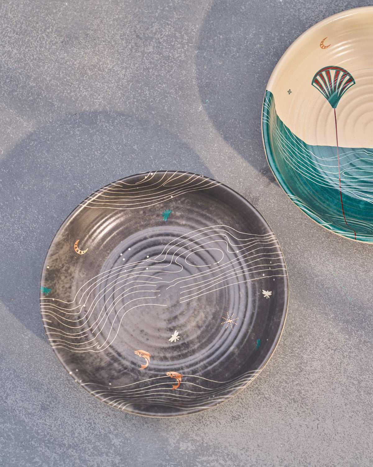 Grey Pacific shallow bowl with white wave lines, next to a teal and cream bowl.
