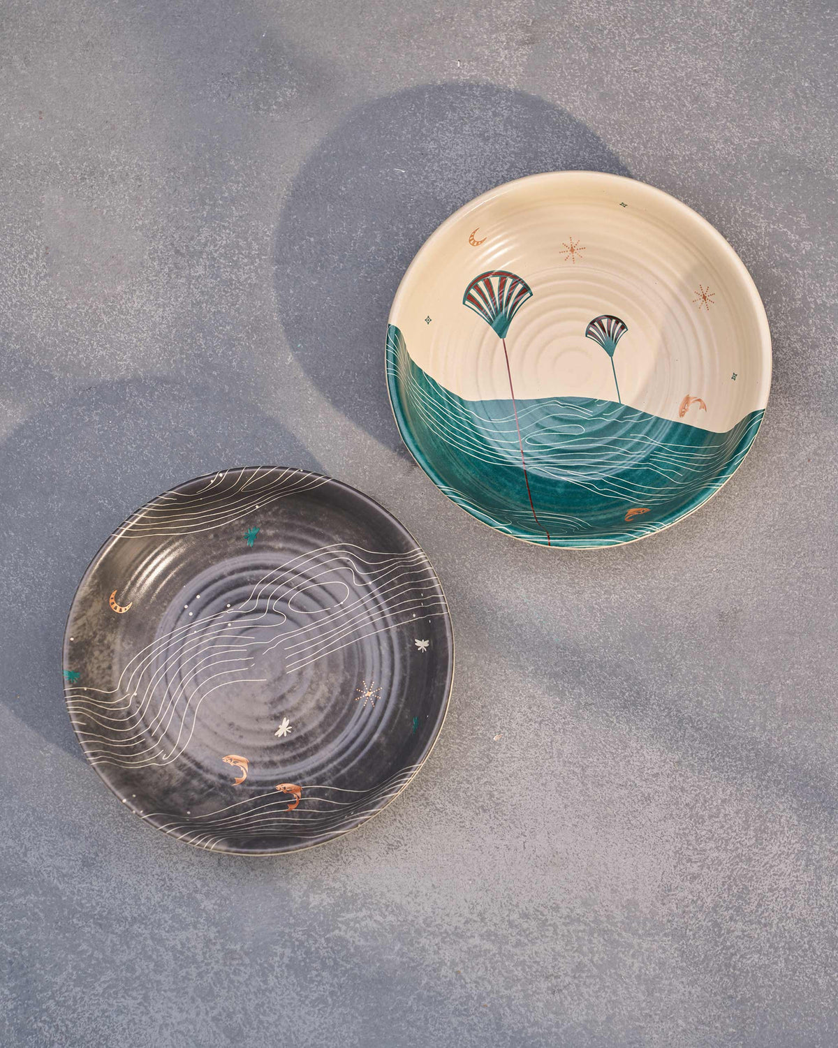 Pair of Pacific shallow bowls seen from above, one grey and one teal and cream.