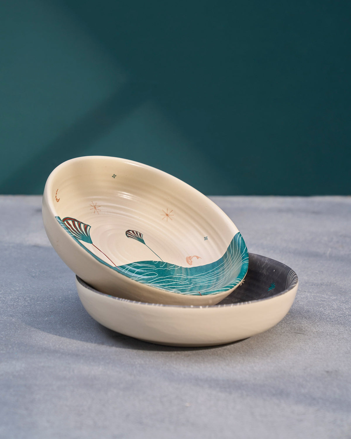 Pacific shallow bowls stacked at an angle, the top one cream with teal waves.