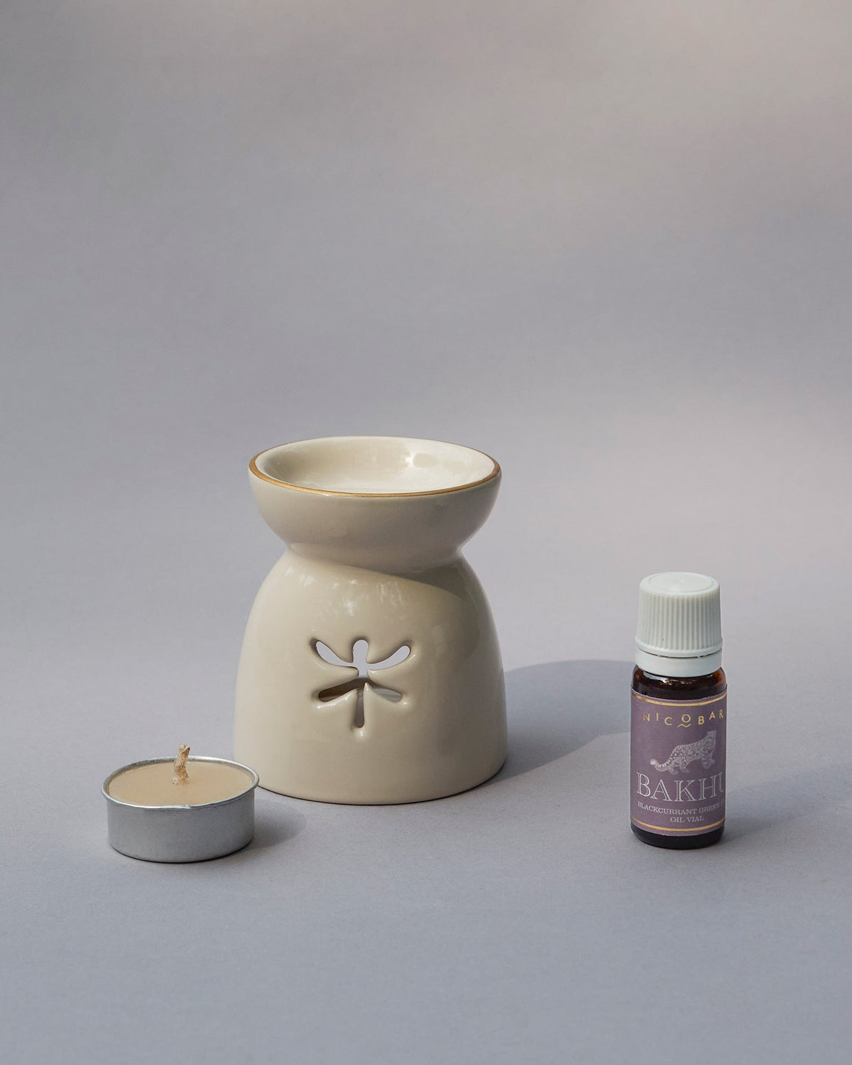 Cream ceramic oil burner with a tealight and a small bottle of oil.