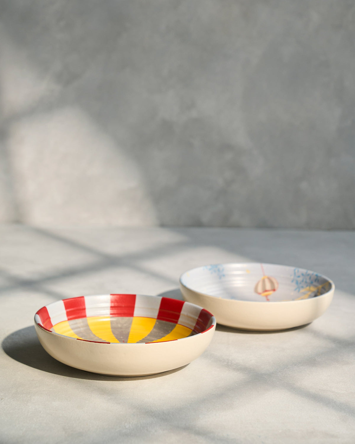 Pair of Chakra Shallow Bowls side by side, one with a painted lantern.