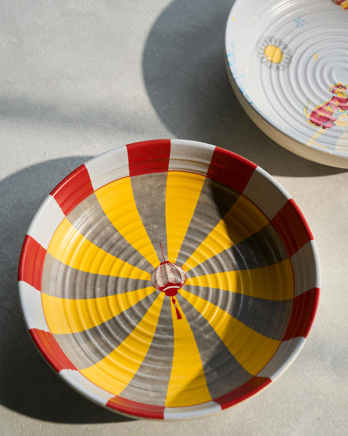 Close-up of a Chakra Shallow Bowl with radiating yellow and red stripes.