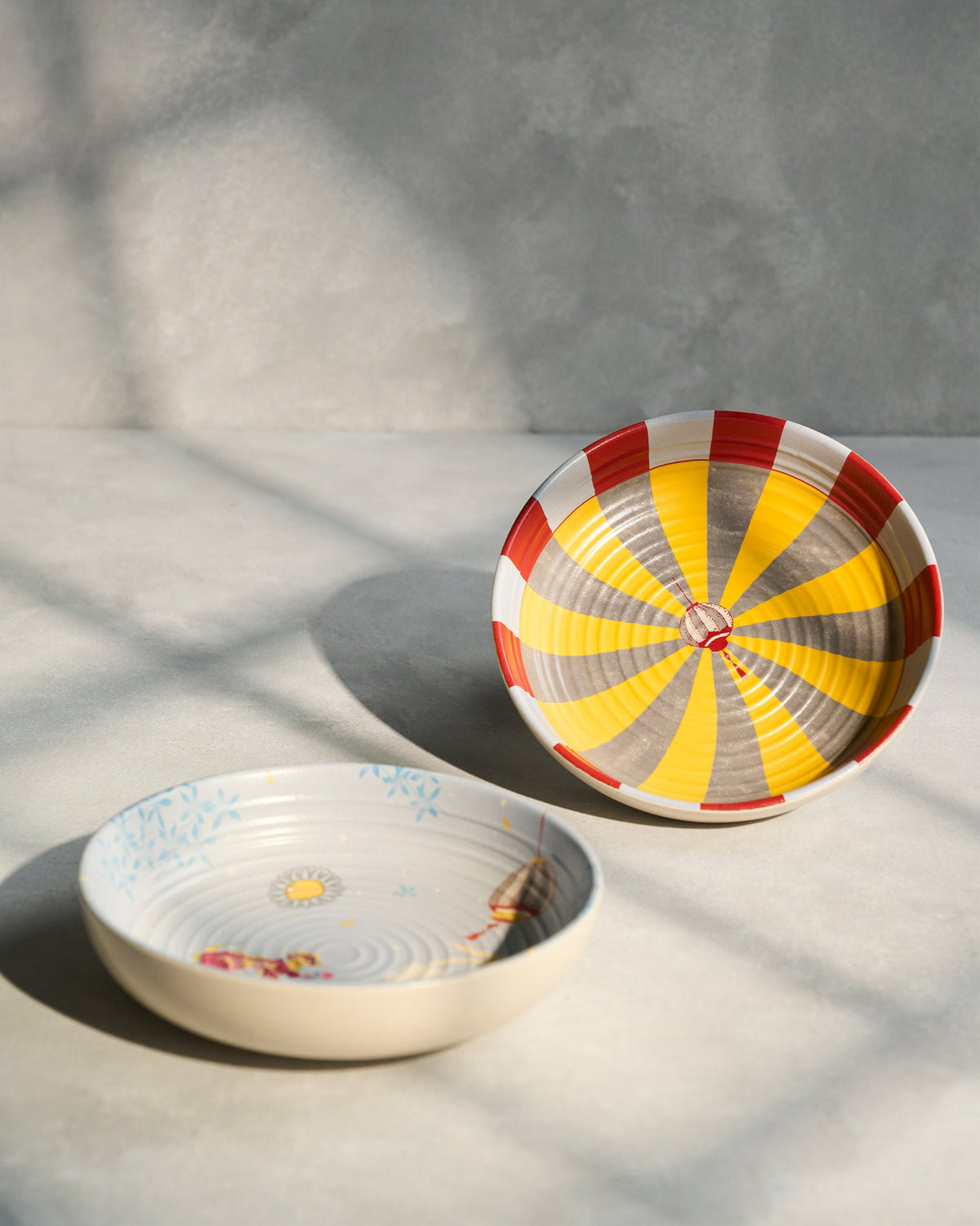 Chakra Shallow Bowl with red and yellow stripes, beside a painted bowl.