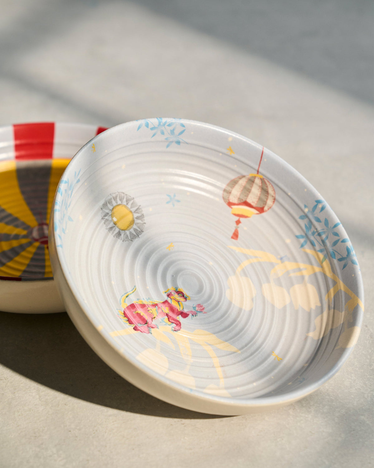 Chakra Shallow Bowl with a painted lantern and sun motif.