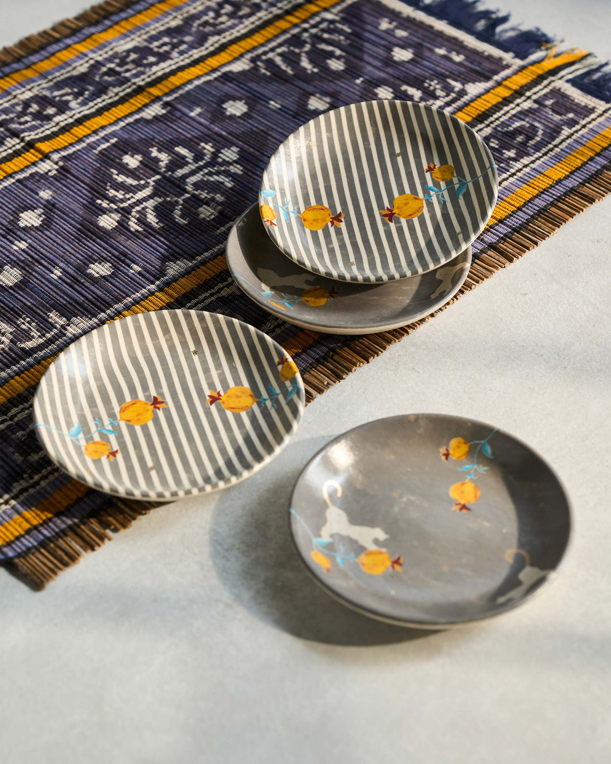 Stacked Anar tea plates with yellow pomegranate motifs.