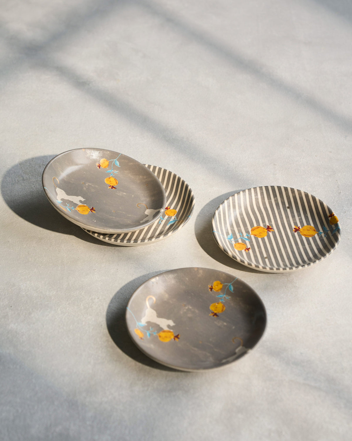 Anar tea plates in grey and striped designs with pomegranate motifs.