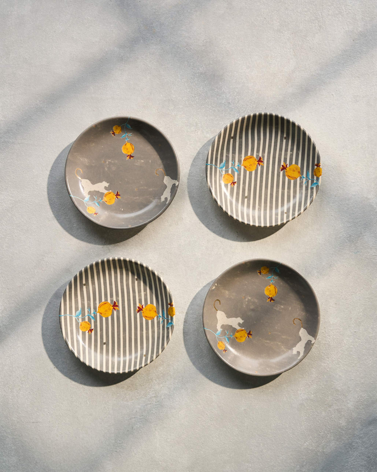 Four Anar tea plates, two grey and two striped, arranged in a square.