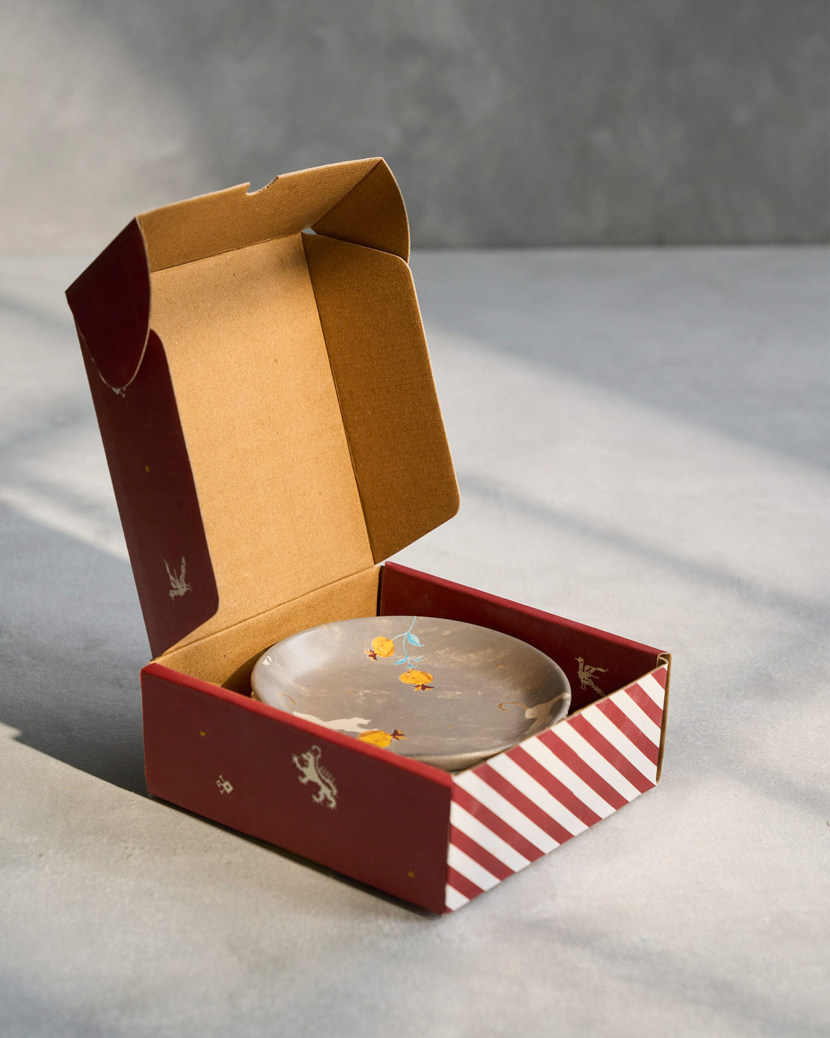 Grey Anar tea plate inside an open Nicobar gift box.