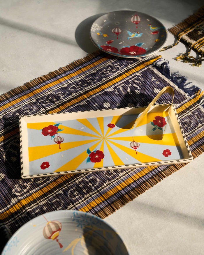 Chakra Cookie Tray with yellow sunburst, red flowers and lanterns on a woven runner.