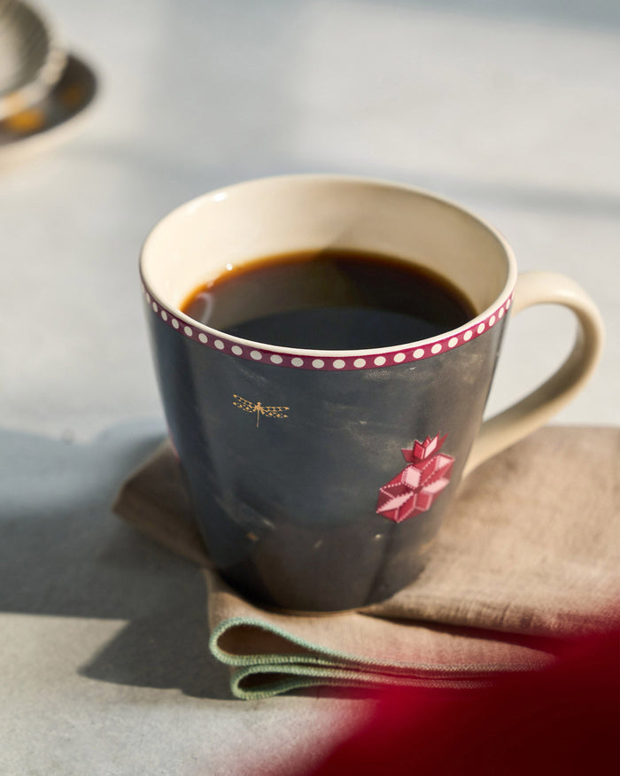 Anar Conical Mug with coffee in it, showing its pink dotted rim and pomegranate motif.