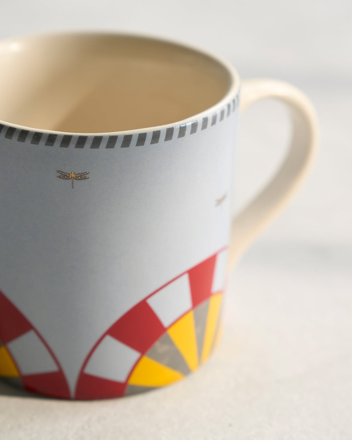 Close-up of a Chakra Straight Mug showing red and yellow arcs and a small insect motif.