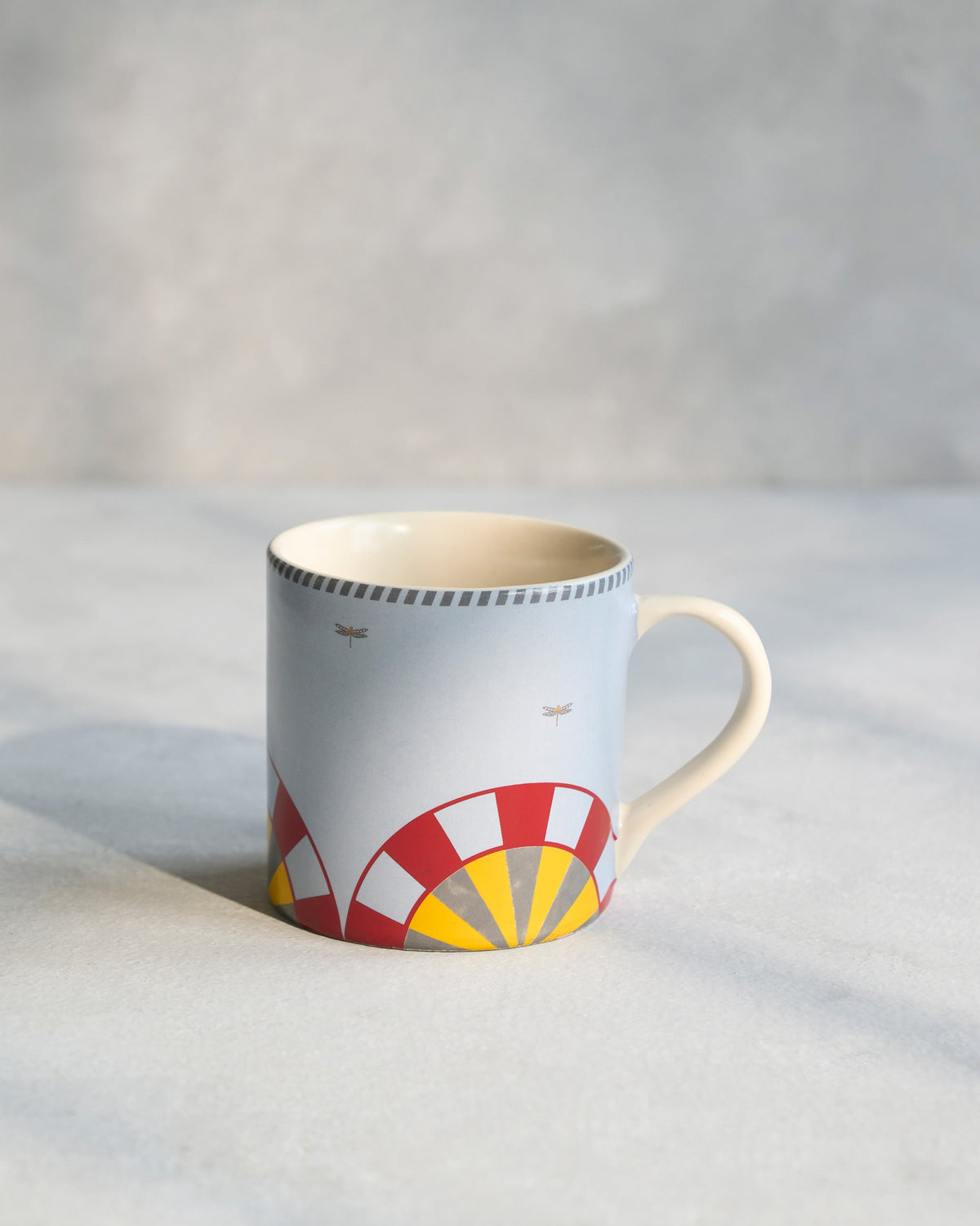 Side view of a Chakra Straight Mug with a red and yellow arc design.