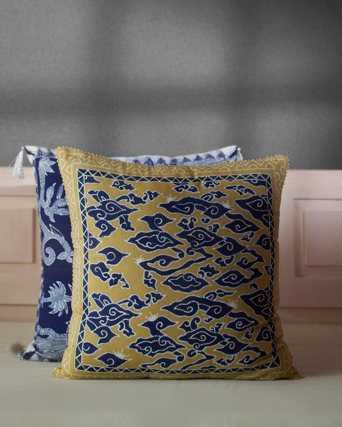 Voyage Cushion Cover in mustard with a blue scroll motif.