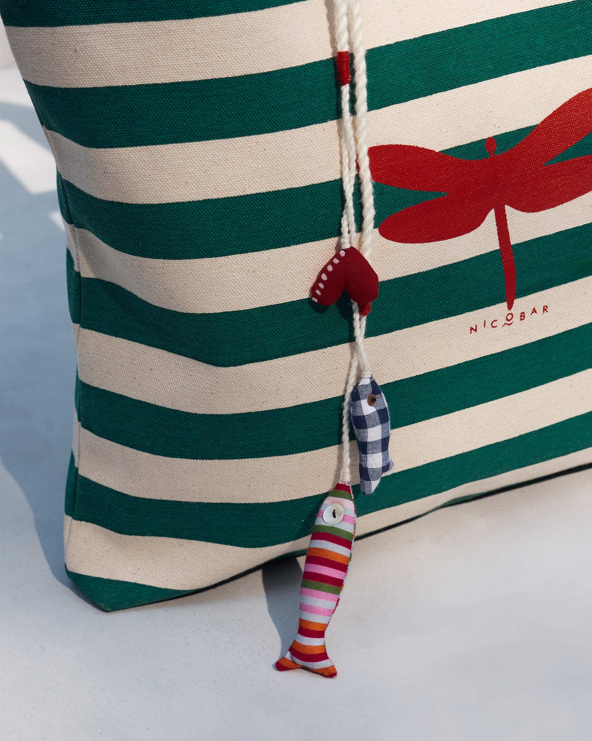 Close-up of a Bagan Stripe Tote with a red dragonfly print and fabric charms.