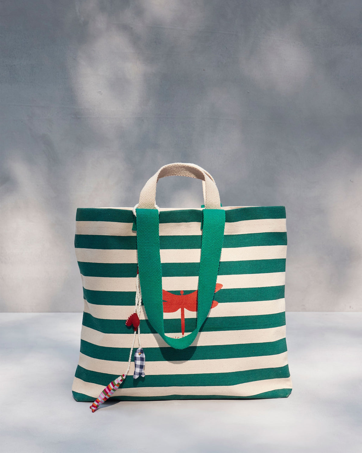 Bagan Stripe Tote with teal handles and a red dragonfly print, standing upright.