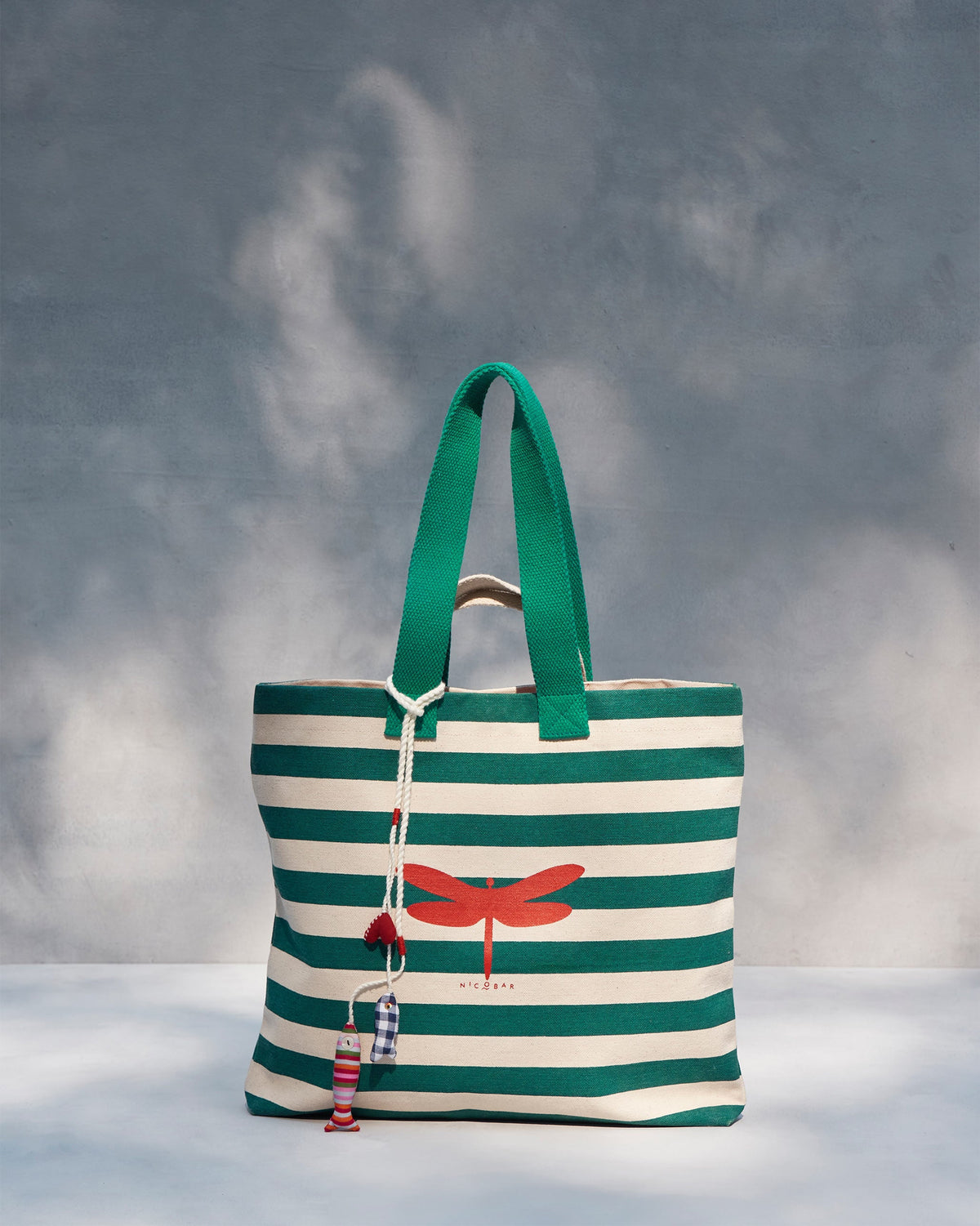 Bagan Stripe Tote with teal handles and fabric charms hanging from the cord.