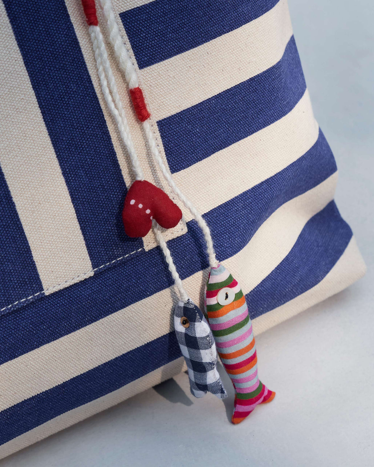 Close-up of a Bagan Stripe Tote corner with fabric charms hanging from a cord.