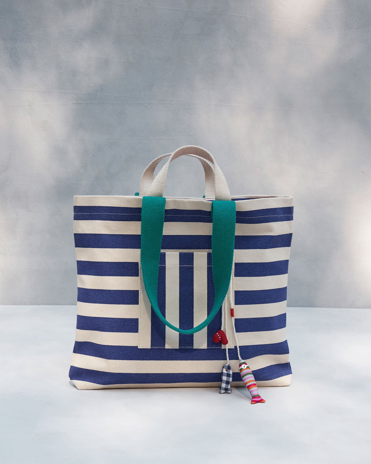 Bagan Stripe Tote with teal handles and a striped pocket, standing upright.