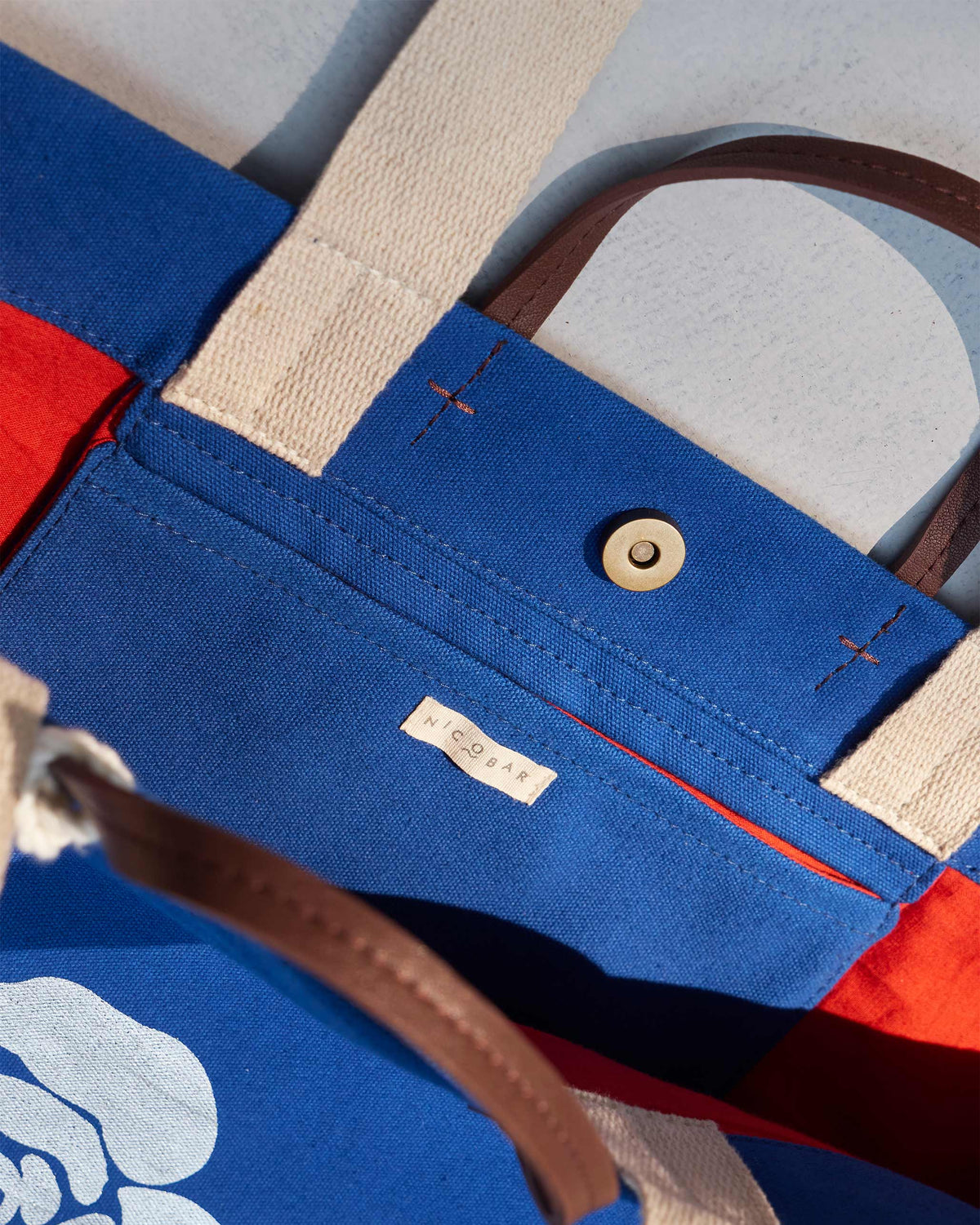 Close-up of a Bodhi Tote pocket flap with a Nicobar label and snap fastening.