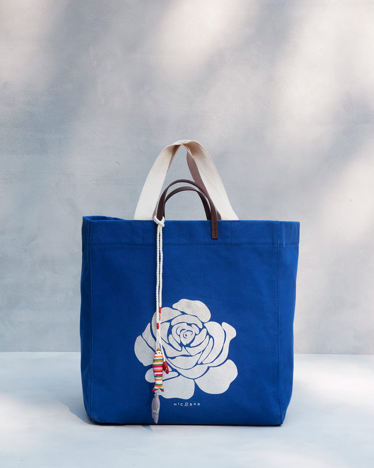 Bodhi Tote standing upright with its white rose print and tassel.