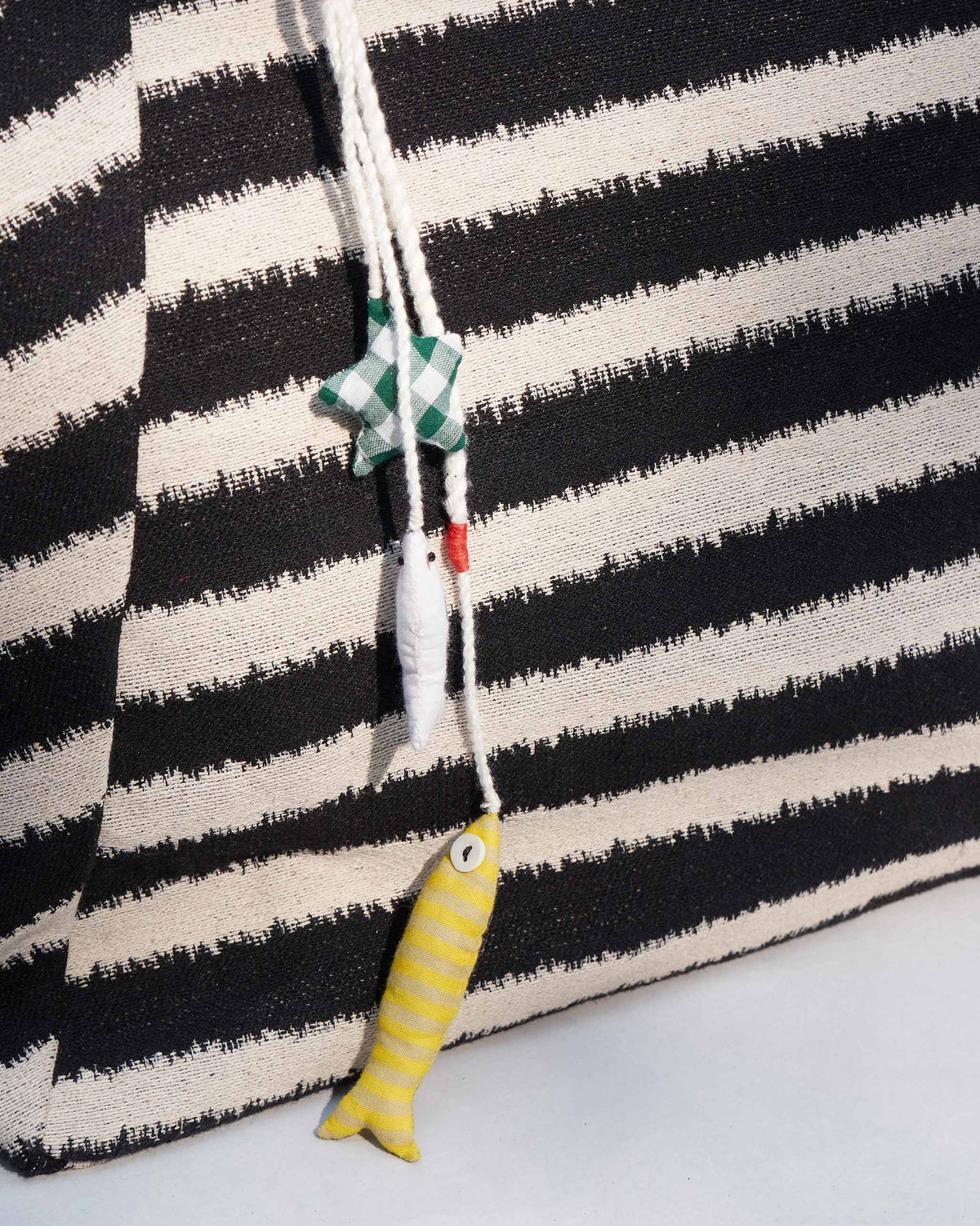 Close-up of a yellow fish charm and green star charm on the Sunrise Stripe Tote.