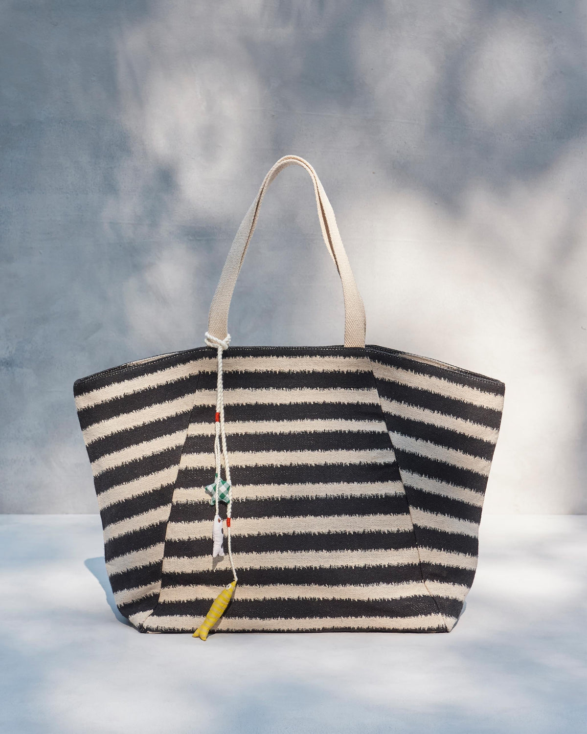Sunrise Stripe Tote standing upright with charms hanging from its rope.