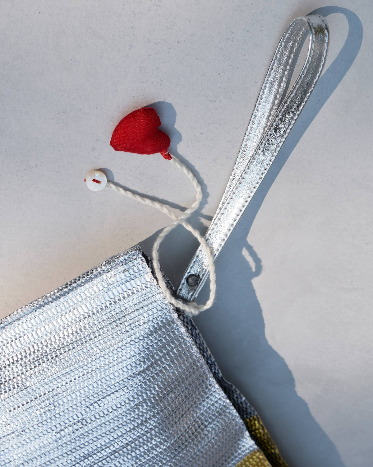 Close-up of the silver corner of the Sitara Clutch with its red heart tassel.