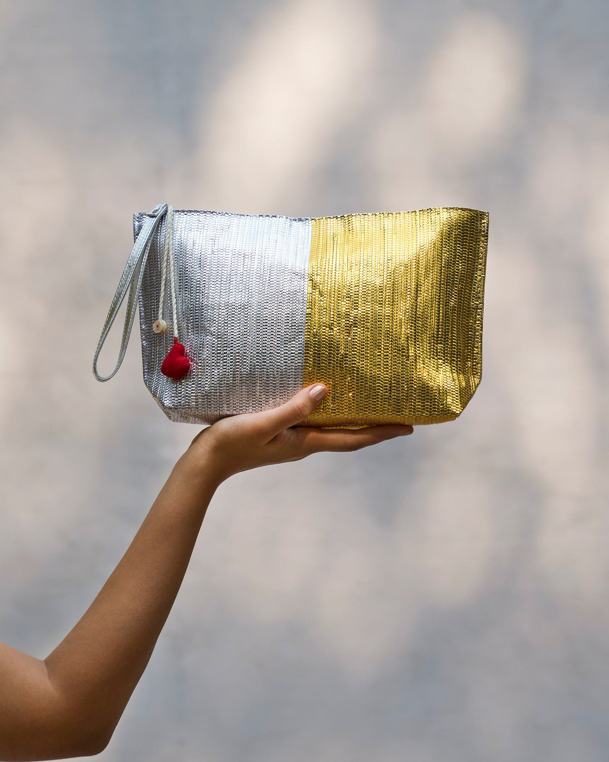 Sitara Clutch held in a hand, with silver and gold panels.