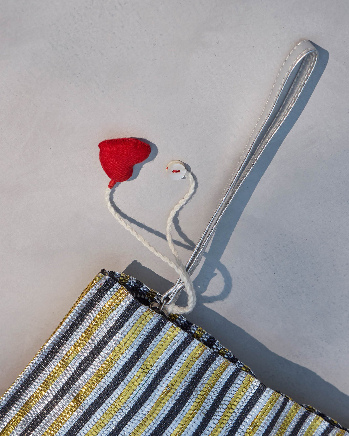 Close-up of the Sitara Clutch corner with a red heart tassel and silver wristlet.