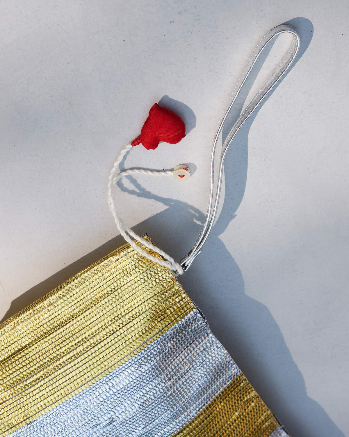 Close-up of the Seher Clutch wristlet strap and red heart tassel.