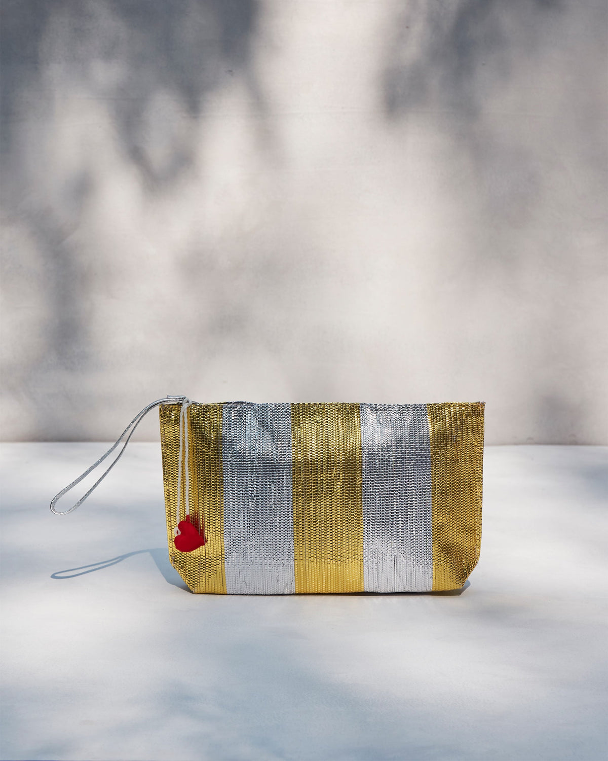 Seher Clutch standing upright, showing its gold and silver stripes.