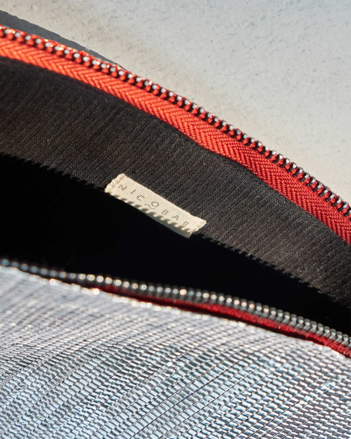 Inside of the Sitara Clutch showing its black lining and orange zip.