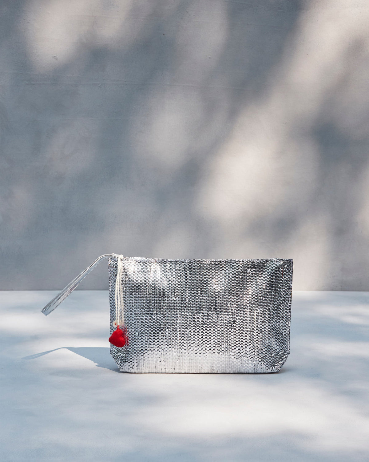 Sitara Clutch standing upright in silver, with a red heart tassel.