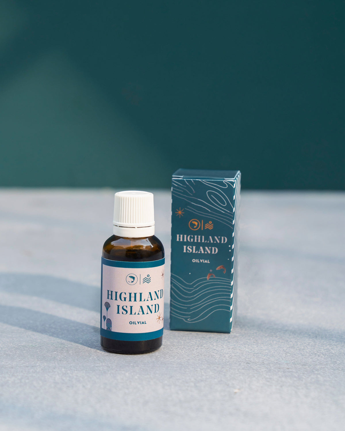 Shell Essential Oil vial standing beside its teal box.