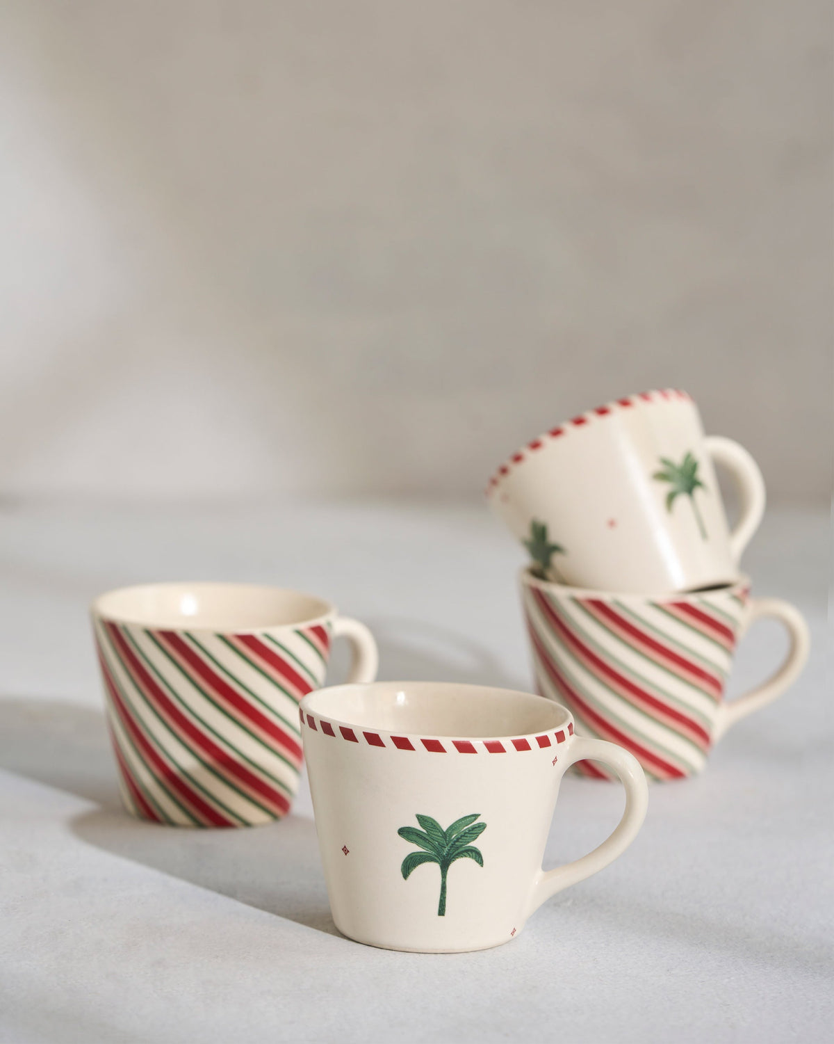 Four Whimsical Espresso Mugs in a loose group, two with palm motifs and two striped.