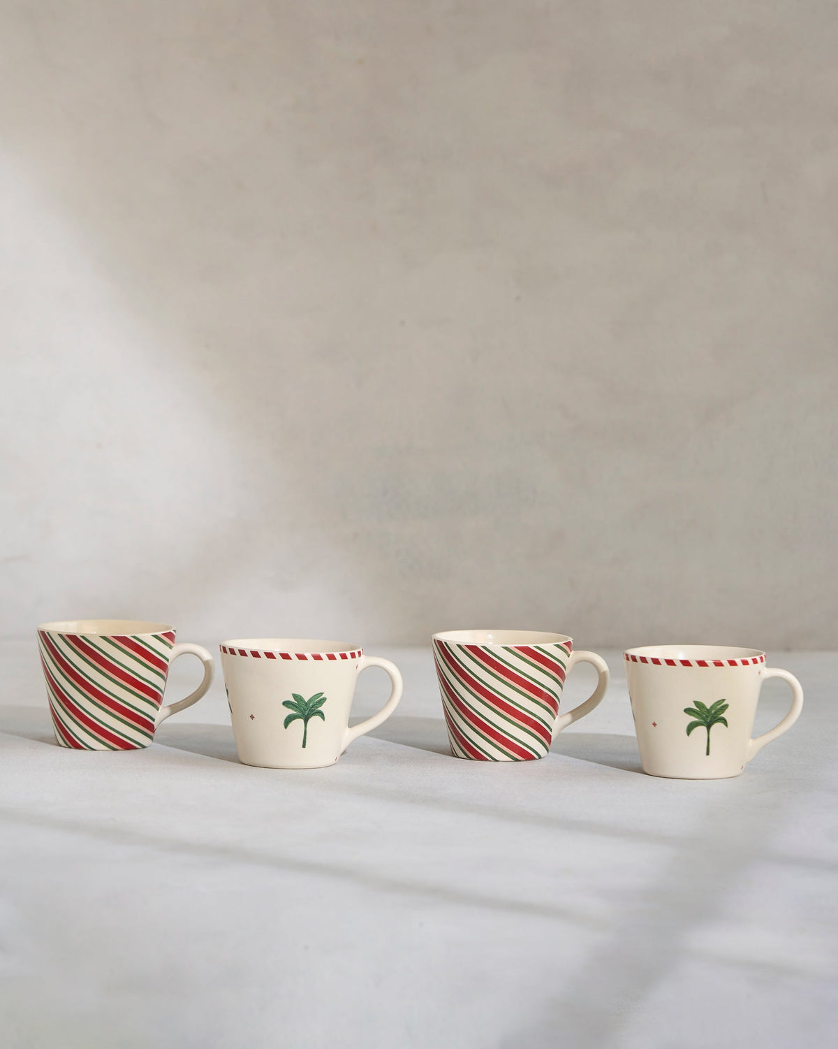 Whimsical Espresso Mugs in a row, alternating striped and palm motif designs.
