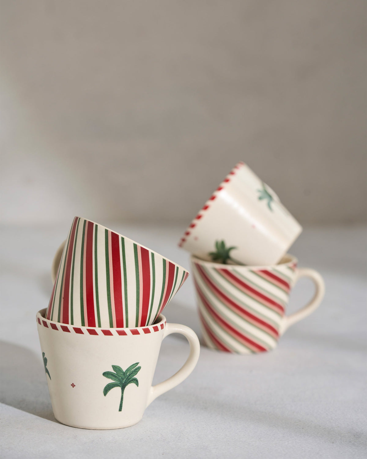 Whimsical Espresso Mugs with palm motifs and red and green stripes, one tipped on its side.
