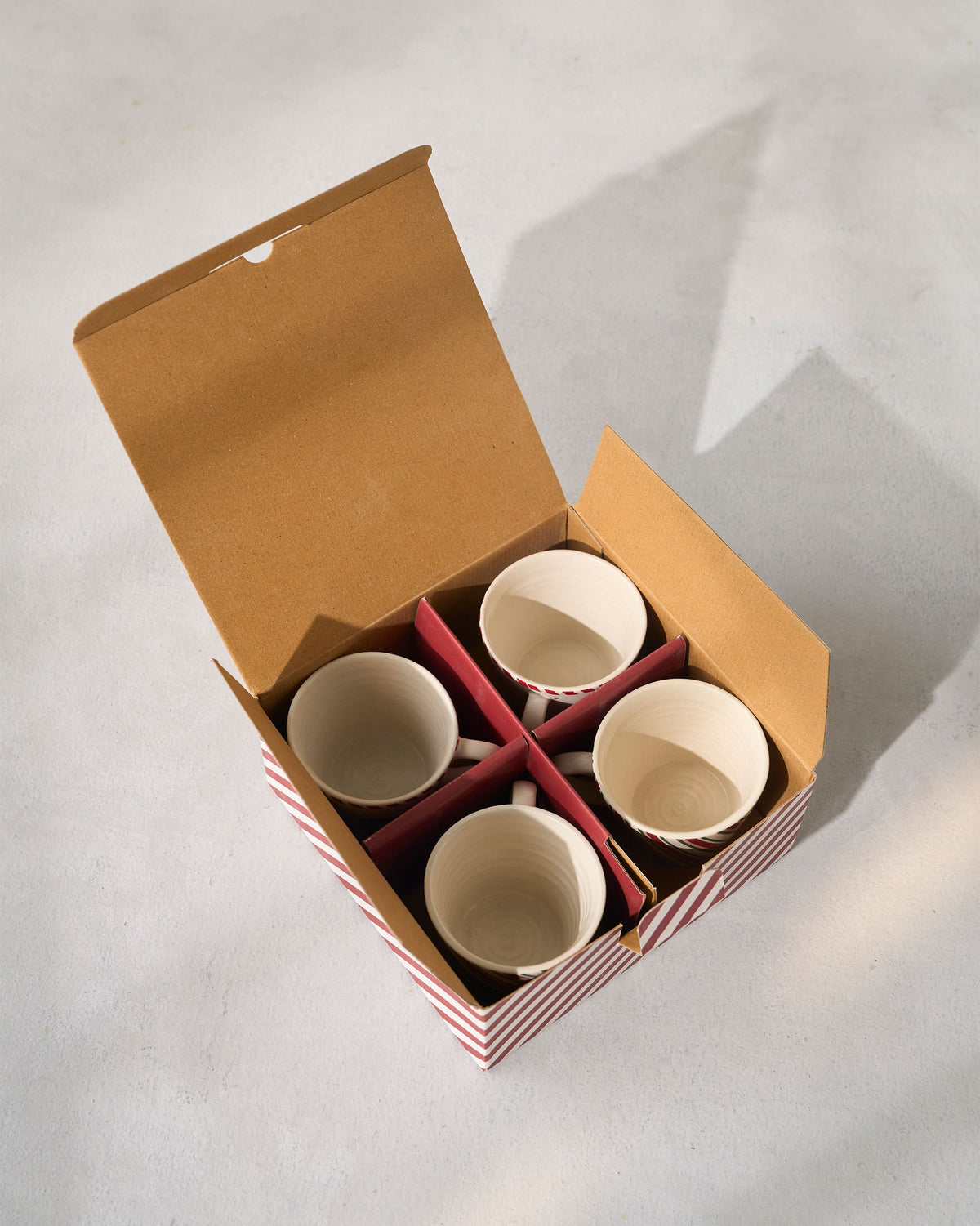 Four Whimsical Espresso Mugs inside an open kraft gift box with red striped sides.