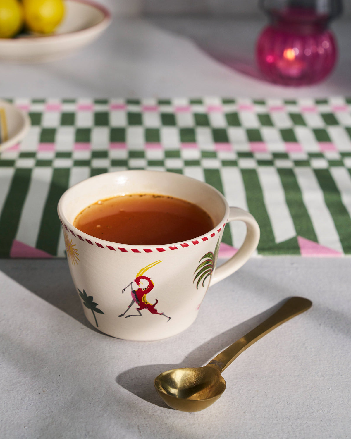 Mare Soup Mug filled with tea, with a gold spoon resting beside it.