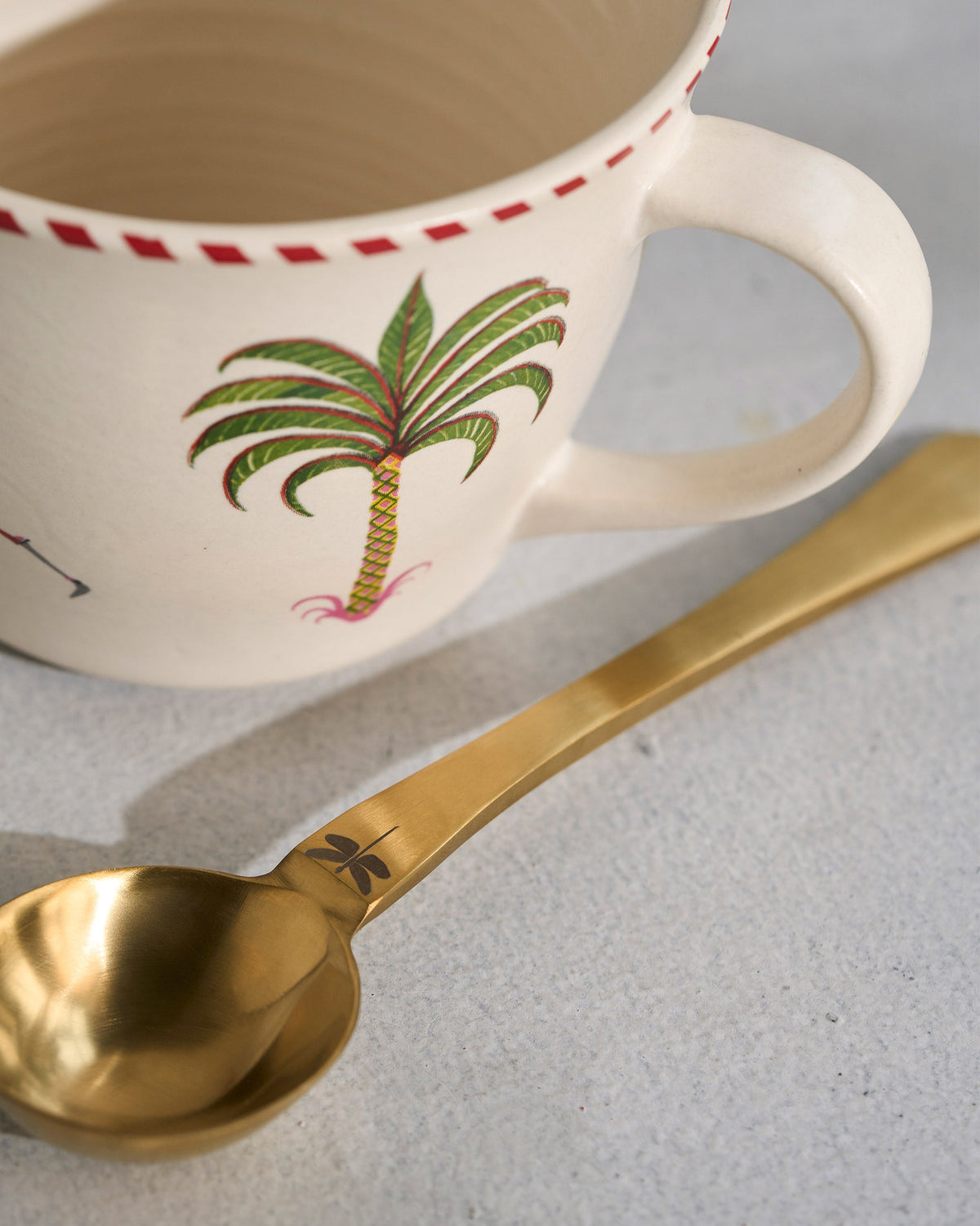 Side view of a Mare Soup Mug with a palm tree and a small yellow animal.