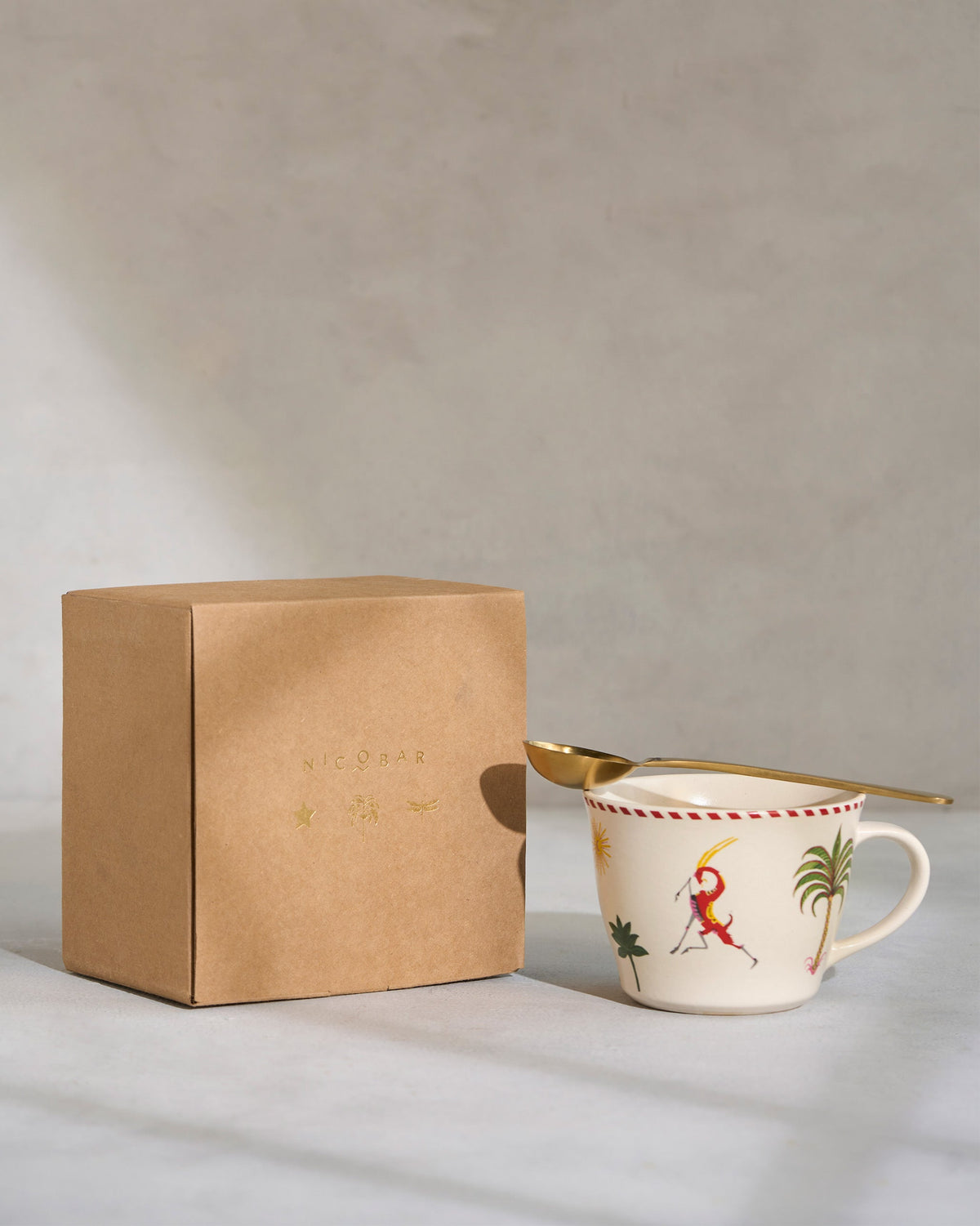 Mare Soup Mug with a gold spoon, beside a Nicobar kraft box.