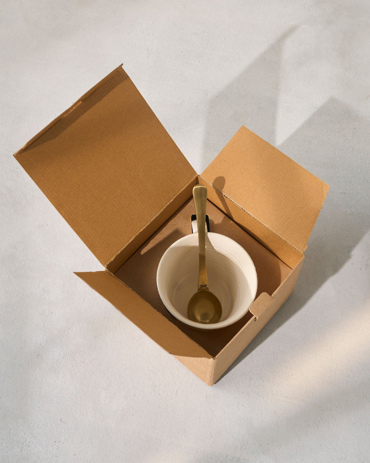 Mare Soup Mug with a spoon, placed inside an open kraft box.