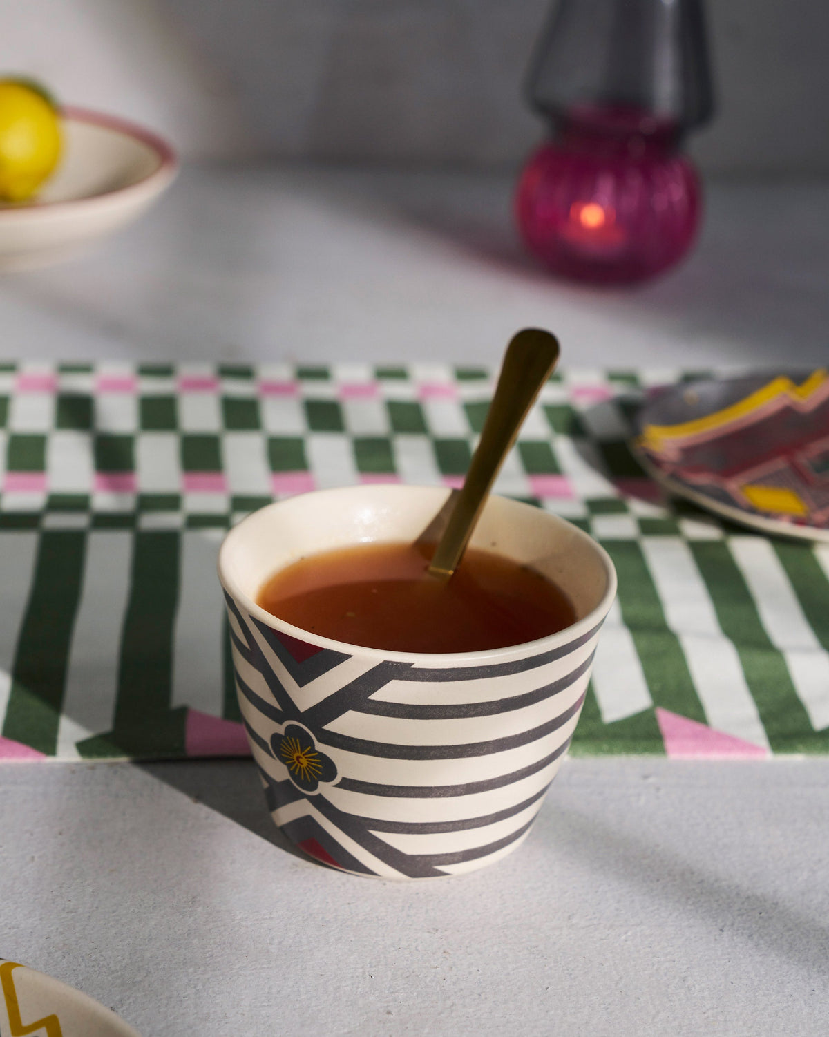 Leafty Affair Soup Mug with Spoon filled with tea and a gold spoon.