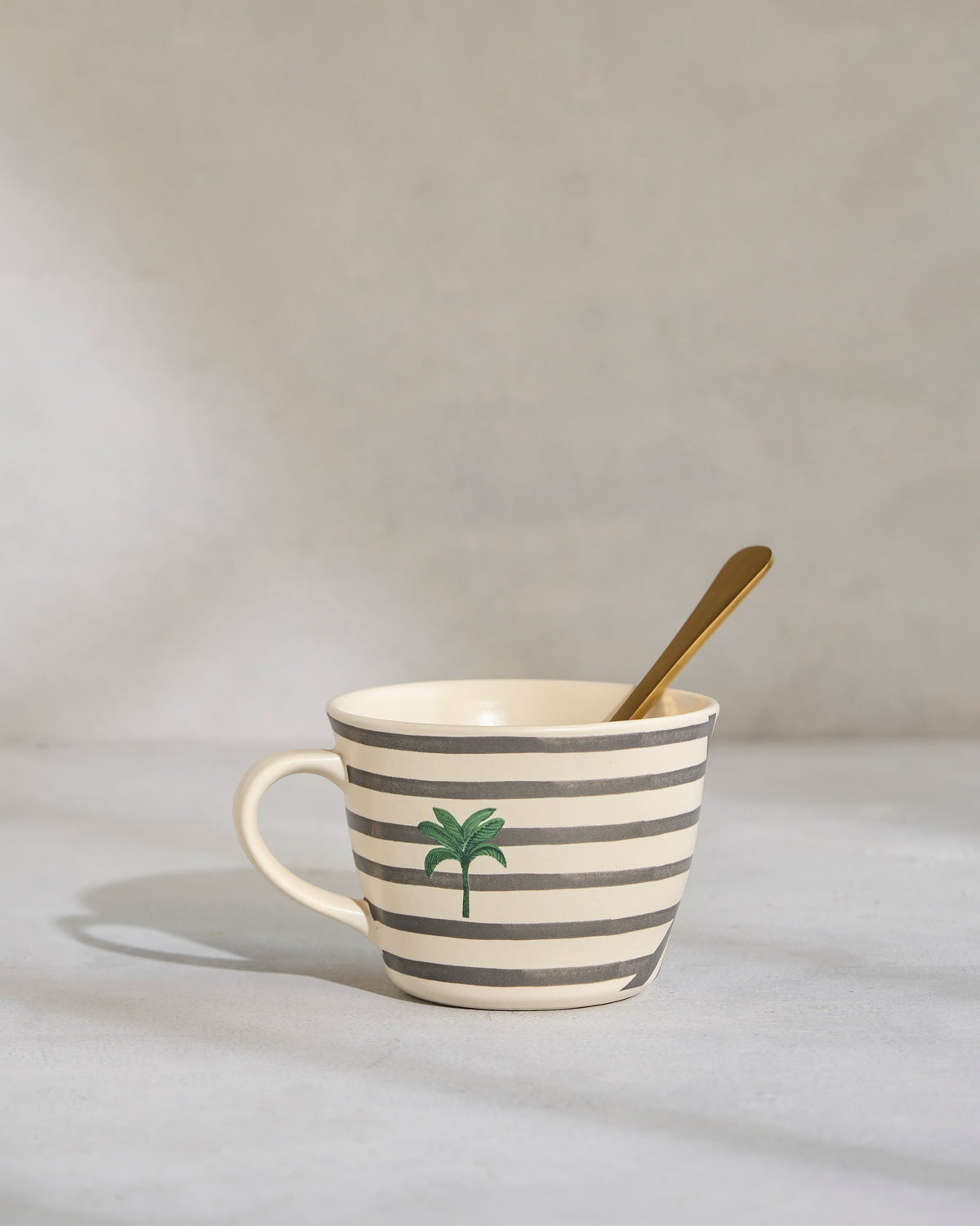 Leafty Affair Soup Mug with a green palm motif and a gold spoon inside.