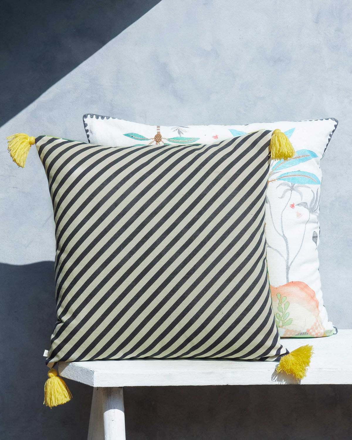 Zanzibar cushion cover in black and sage diagonal stripes with yellow tassels.