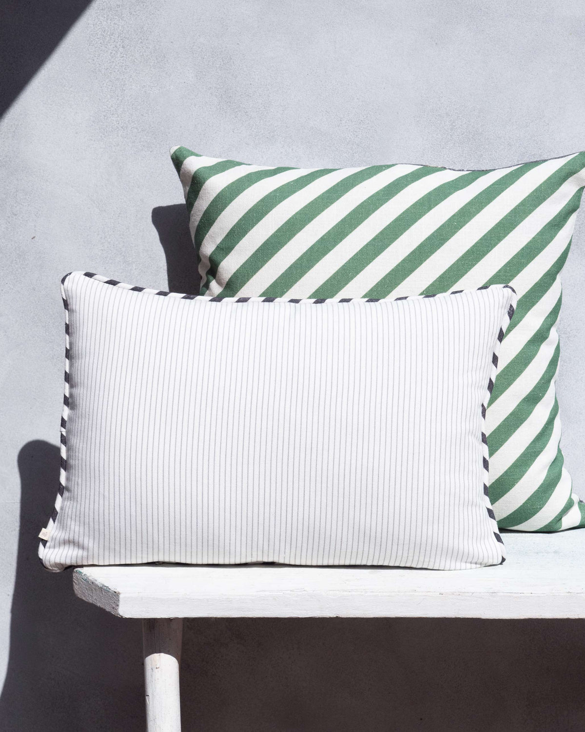 Flamingo Cushion Cover in white pinstripe with dark piping along the edges.