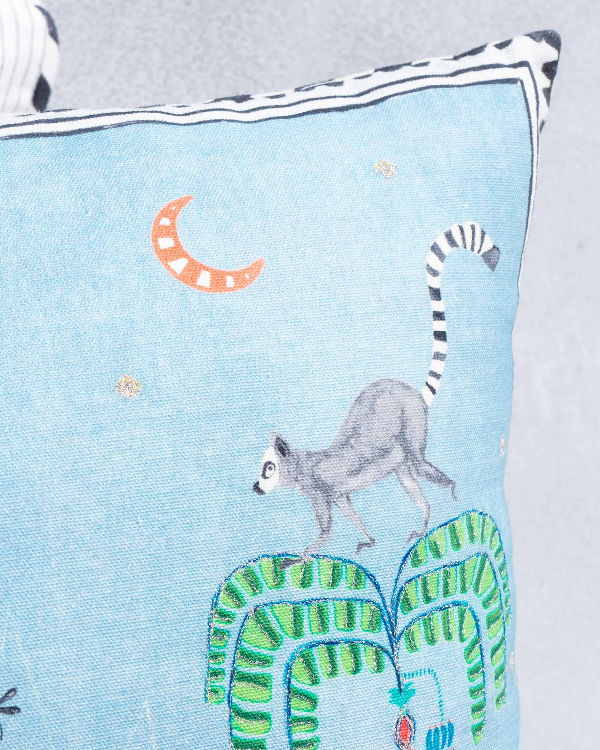 Close-up of Jungle Blue Cushion Cover showing a lemur, crescent moon and green foliage.