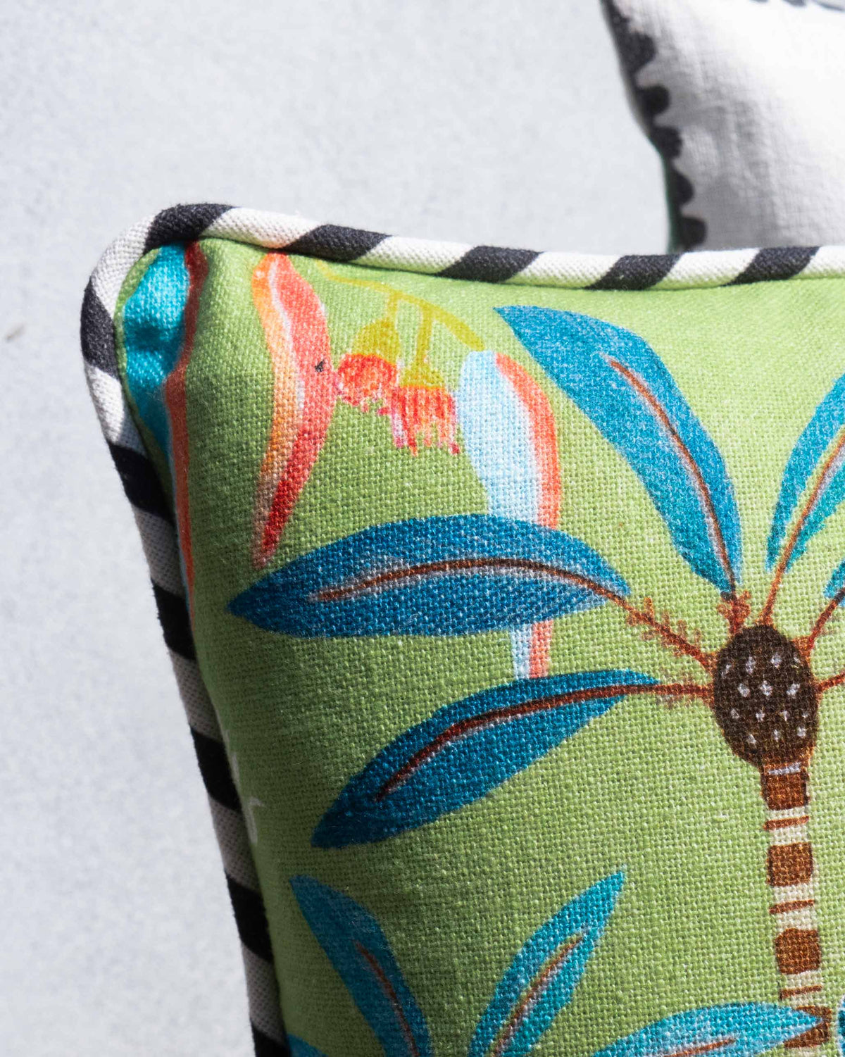 Close-up of the Wilderness Cushion Cover showing palm leaves and black-and-white trim.
