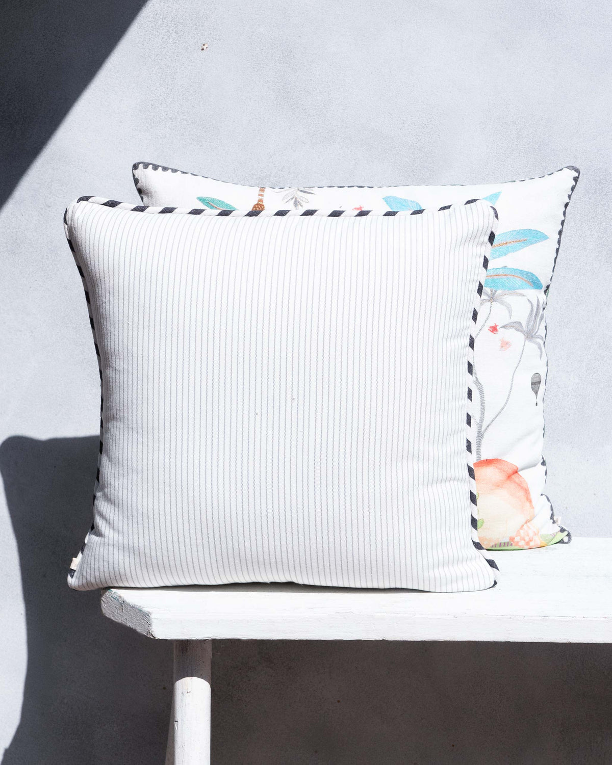 Back of the Wilderness Cushion Cover in cream pinstripe with black-and-white trim.